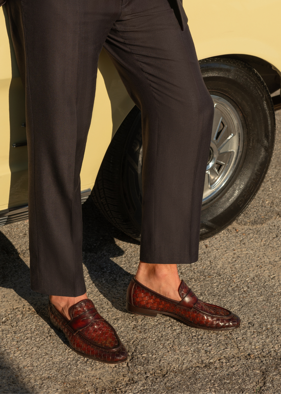 man wearing brown loafers leaning on a car