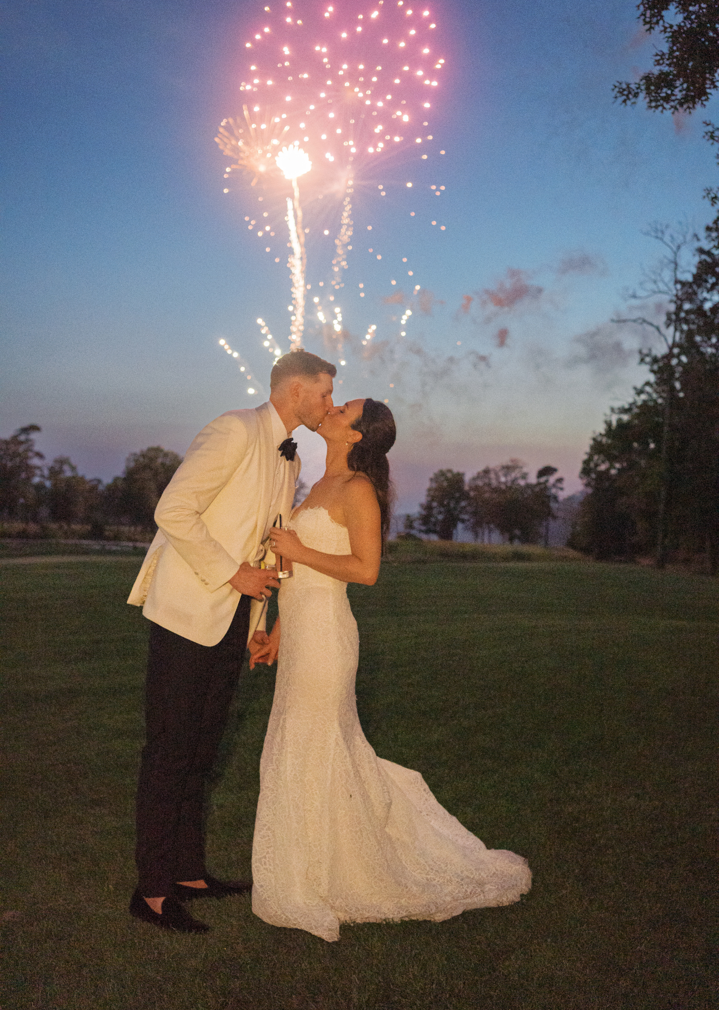 Bride & Groom kissing with fireworks behind them.